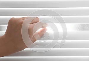 Young woman opening window blinds, closeup.