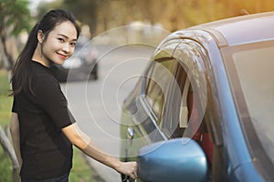 Young woman opens door of blue metallic car