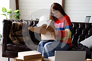 A young woman opens a parcel from an online store, delivering goods to a consumer
