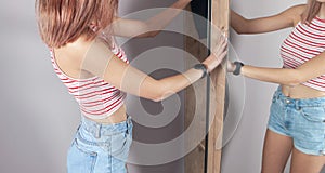Young woman opens the wardrobe door at home