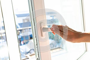 A young woman opens a white window at home