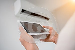 Young woman operates wireless aircon system in a modern apartment.