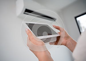 Young woman operates wireless aircon system in a modern apartment. photo