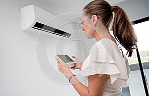 Young woman operates wireless aircon system in a modern apartment. photo