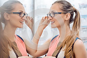 Young woman in optometrists store checking her looks in mirror