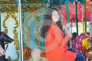 Young woman in orange coat carousel horseback outdoor portrait