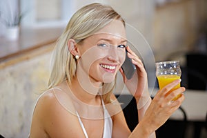 Young woman with orange juice and smart phone