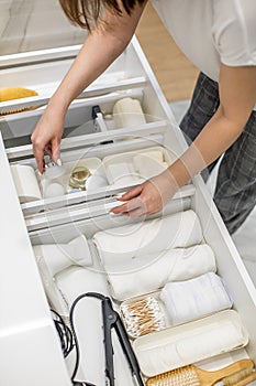 Young woman organizing bathroom storage, displaying beauty cosmetic creams and toiletries in drawer