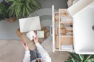 Young woman organizing bathroom storage, displaying beauty cosmetic creams and toiletries in drawer