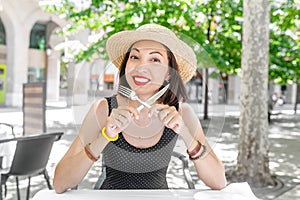 Young woman in outdoor restaurant with a knife and fork in her hands