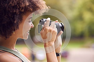 Young Woman Outdoors With DSLR Camera Taking Photos In City Park