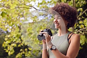 Young Woman Outdoors With DSLR Camera Taking Photos In City Park