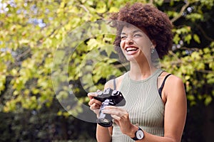 Young Woman Outdoors With DSLR Camera Taking Photos In City Park