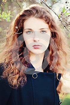 Young Woman Outdoors. Girl with Red Curly Hair