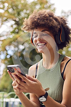 Young Woman Outdoors Wearing Wireless Headphones Streaming Show From Mobile Phone 