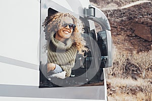 Young woman outside the window of her modern camper van motor home enjoy arrival travel destination admiring the outdoors. Concept