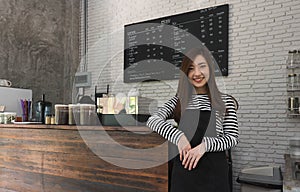 Young woman owner of a cafe stand in front of coffee counter, yo