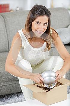 young woman packing moving box in room at home