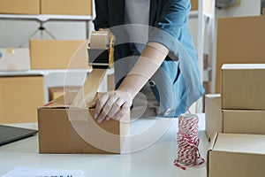 Young woman packing product in box for online order.