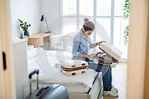 Young woman packing suitcase in the bedroom