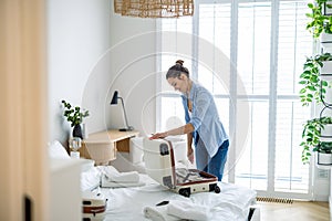 Young woman packing suitcase in the bedroom