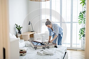 Young woman packing suitcase in the bedroom