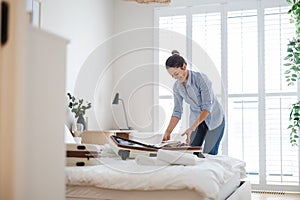 Young woman packing suitcase in the bedroom