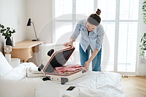 Young woman packing suitcase in the bedroom