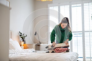 Young woman packing suitcase in the bedroom