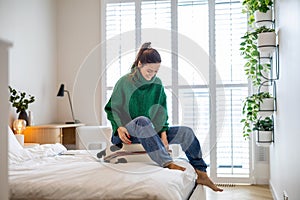 Young woman packing suitcase in the bedroom