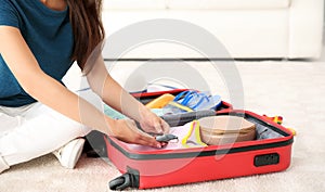 Young woman packing suitcase at home