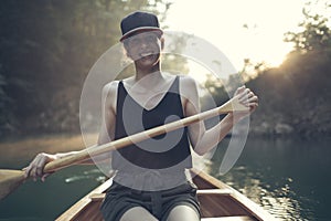 Young woman paddling canoe on a forest lake