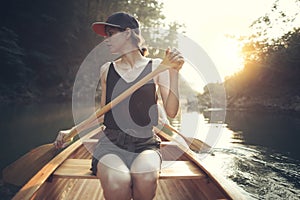 Young woman paddling canoe on a forest lake