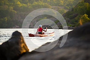 Young Woman Paddling the Red Kayak on Beautiful River or Lake in the Mountains