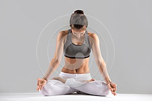 Young woman in Padmasana pose, grey studio background photo