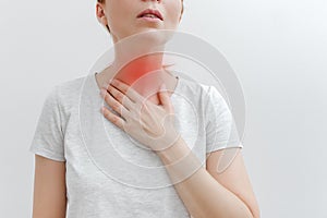 Young woman with pain in throat, toothache. Red mark. Women touches the throat. White background. Close-up view