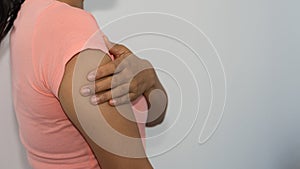 Young woman with pain in the upper arm and shoulder, holding her hand, medical concept