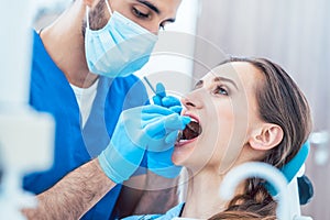 Young woman during painless teeth cleaning done by a reliable de