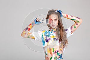 Young woman smeared in multicolored paint.