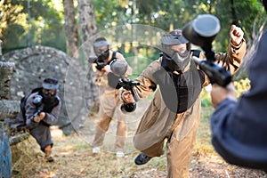 Young woman paintball player rushing through enemy lines