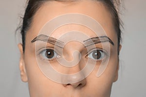 Young woman with painted contours of eyebrows before painting them, closeup.