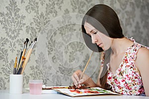 Young woman painter drawing watercolor poppies at her home studio