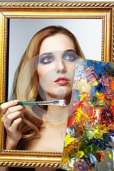 Young woman painter in golden frame with color pallet and paint