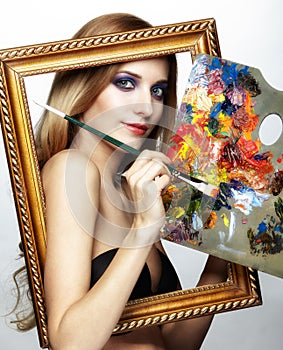 Young woman painter in golden frame with color pallet and paint