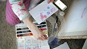 Young woman painting artist at home sitting on the floor creative painting