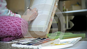 Young woman painting artist at home sitting on the floor creative painting