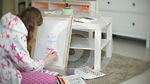 Young woman painting artist at home sitting on the floor creative painting