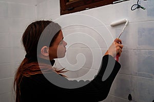 Young woman painting bathroom ceramic  wall tiles ,do it your self ,renovation