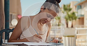 Young woman painting canvas outdoors in terrace with glass of water at summer