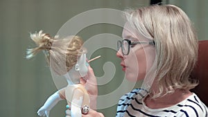 Young woman is painting a doll making her scary